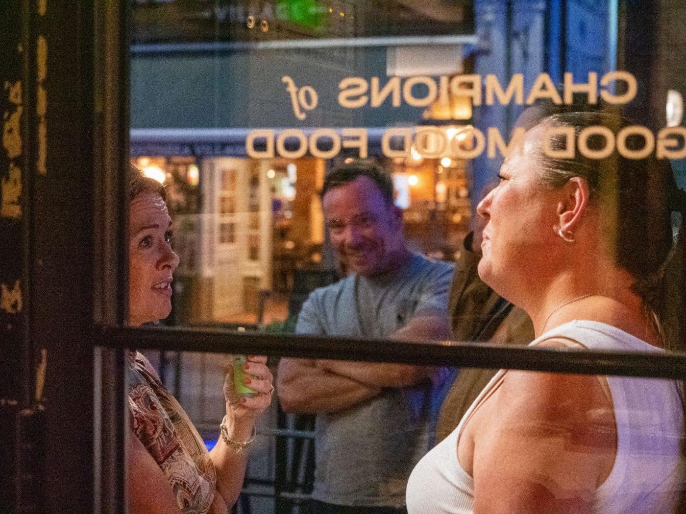 Guests talking outside the window of Croxtons under the Champions of Good Mood Food signage